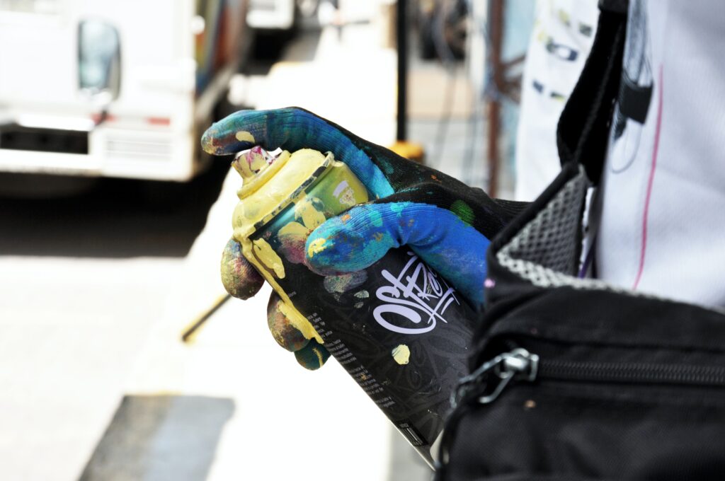 Bilden visar en person med en sprayburk. Sprayfärger, möbelfärger och snickerifärger finns med antingen RAL kulör eller NCS kulör.